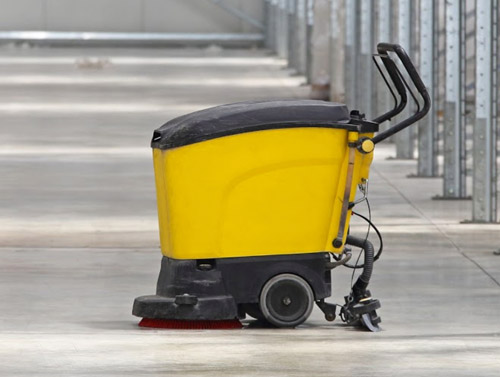 Yellow commercial floor scrubber cleaning a facility